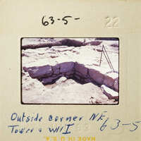 A photograph showing an excavation site with stone ruins and a small tent set up nearby.