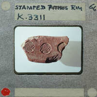 An old, weathered clay artifact with markings on it, displayed against a light background and photographed to appear as if it's a slide from an educational presentation.