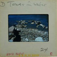 A vintage photograph of a rocky shoreline with water and a tower, labeled "Tower in Water".