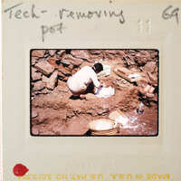 A person sitting on the ground, working with a pottery wheel and clay.