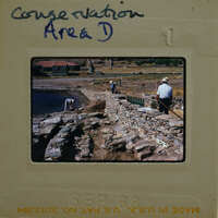 A vintage photograph of a man working on stone walls with a handwritten label "CONSERVATION AREA & D".