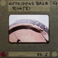 Ancient clay pot with writing on its side, displayed in an exhibition setting.