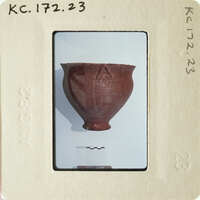 Brown clay pot with markings on display.