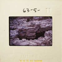 Old photograph on film strip depicting rock formations and ruins.