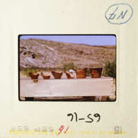 A photo of pottery on display, with a mountainous landscape in the background.