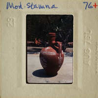 A clay vase with decorative patterns on a concrete surface.