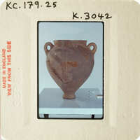 Ancient clay pot with visible cracks and chips, displayed on a stand.