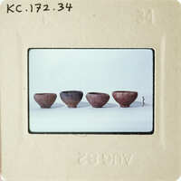 Row of four clay pots on a white surface.
