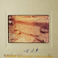 This is an old photograph of a dirt mound with rocks on top, possibly from an archaeological site.