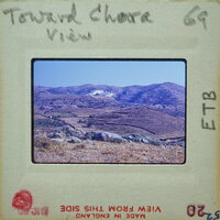 Old photograph of a mountainous landscape with dirt roads and fields, enclosed by an aged film strip border.