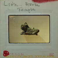 A bronze sculpture of a lion from the side in poor condition.