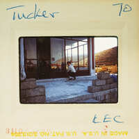 A vintage photo of a person kneeling with mountains in the background.