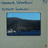 A vintage photograph of a coastal landscape with mountains and water, labeled "Edward Voutsi" on the border.