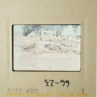 The photo shows an ancient stone structure, possibly ruins, with a barren landscape and a clear sky in the background.