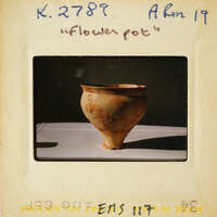 Ancient pottery on display with visible cracks and wear, photographed against a neutral background.