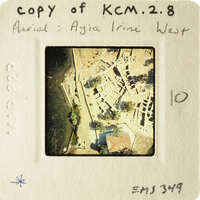 An aerial photograph of an ancient city, possibly Ayia Irini West, displayed on a small card with handwritten notes and numbers.