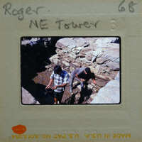 Two men working together on a rocky surface, possibly constructing or repairing a wall.