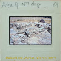 The image shows an old, crumbling stone structure with a dirt ground and sparse vegetation.