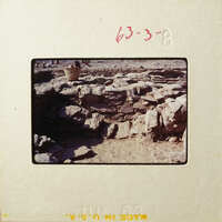 Ancient ruins with stone walls and a dirt floor, possibly an archaeological site.