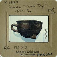 Ancient pottery displayed on a white surface with a label and barcode.