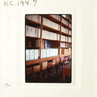 A photograph of an indoor setting with numerous file cabinets and shelves filled with files, taken from a low angle.