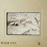 The photo shows an archaeological site with stone structures and rubble, captured by a vintage camera.