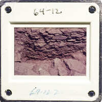 A photograph of an old rock formation with layers and crevices, taken from a low angle.