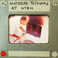 A man operating a pizza oven with a wooden paddle.