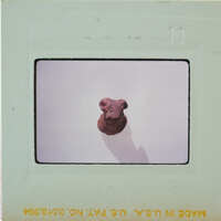 A small, brown dog figurine on a white surface with a shadow cast behind it.