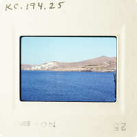 A photograph showing a serene blue water body with a hillside and sky background, placed on a film strip.