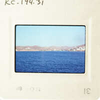 This is an image of a serene blue ocean with mountains in the distance, captured on a photographic slide.