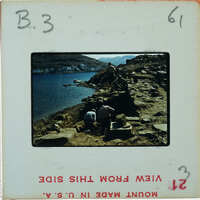 A vintage photograph of a rocky coastline with people working on stone construction.