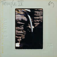 Detail of a stone wall with a modern hose running through it.