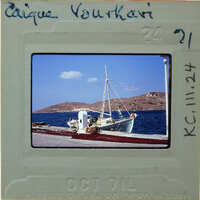 A vintage photograph of a boat docked at a pier with mountains in the background.