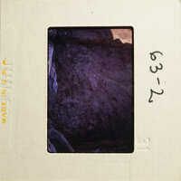 An antique photograph with an illegible date and location stamp on its border, depicting a blurred scene within a dark interior.