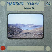 A vintage film strip showing a scenic harbor view with mountains and water.
