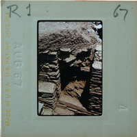 Old stone ruins with a focus on the crumbling wall and archway, possibly from an ancient civilization or historical site.