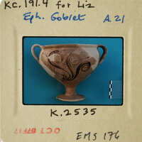 Ancient Greek vase with intricate designs on a blue background, displayed against a white wall.