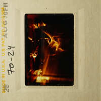 The photo shows a vintage film strip with a blurry image of a person and a fire, possibly indicating an emergency situation.