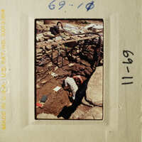 A man working on an archaeological site, surrounded by tools and materials.