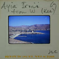 Photo of a coastal landscape with clear blue water and mountains, possibly from an old photo album.