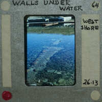 A photograph of a shallow body of water with rocks and debris, enclosed within an old-fashioned film strip frame.