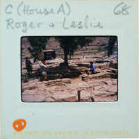 A vintage photo of a man and woman standing near an outdoor stone structure with trees in the background, labeled "House A" and dated "68."