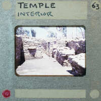 Stone building, possibly a temple interior, with visible ruins and a doorway leading to another room.