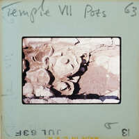 Pottery in situ on surface in stone walled room.