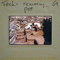 Two people working on a stone wall with hand tools.