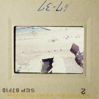 Archaeological trench with framed opening in floor and some rocks or rubble.