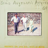 Old photograph of four people standing outside a stone building, with handwritten notes on the border.