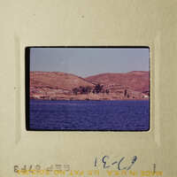 A tranquil view of a serene lake with hills and a clear sky.