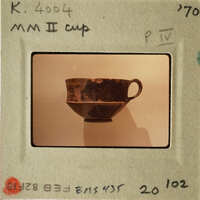 A photograph of an ancient ceramic cup on display.